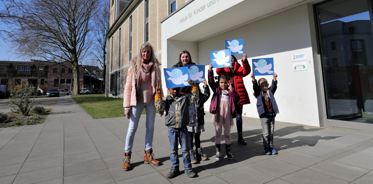 Kinder zeigen selbstgebastelte Friedenstauben